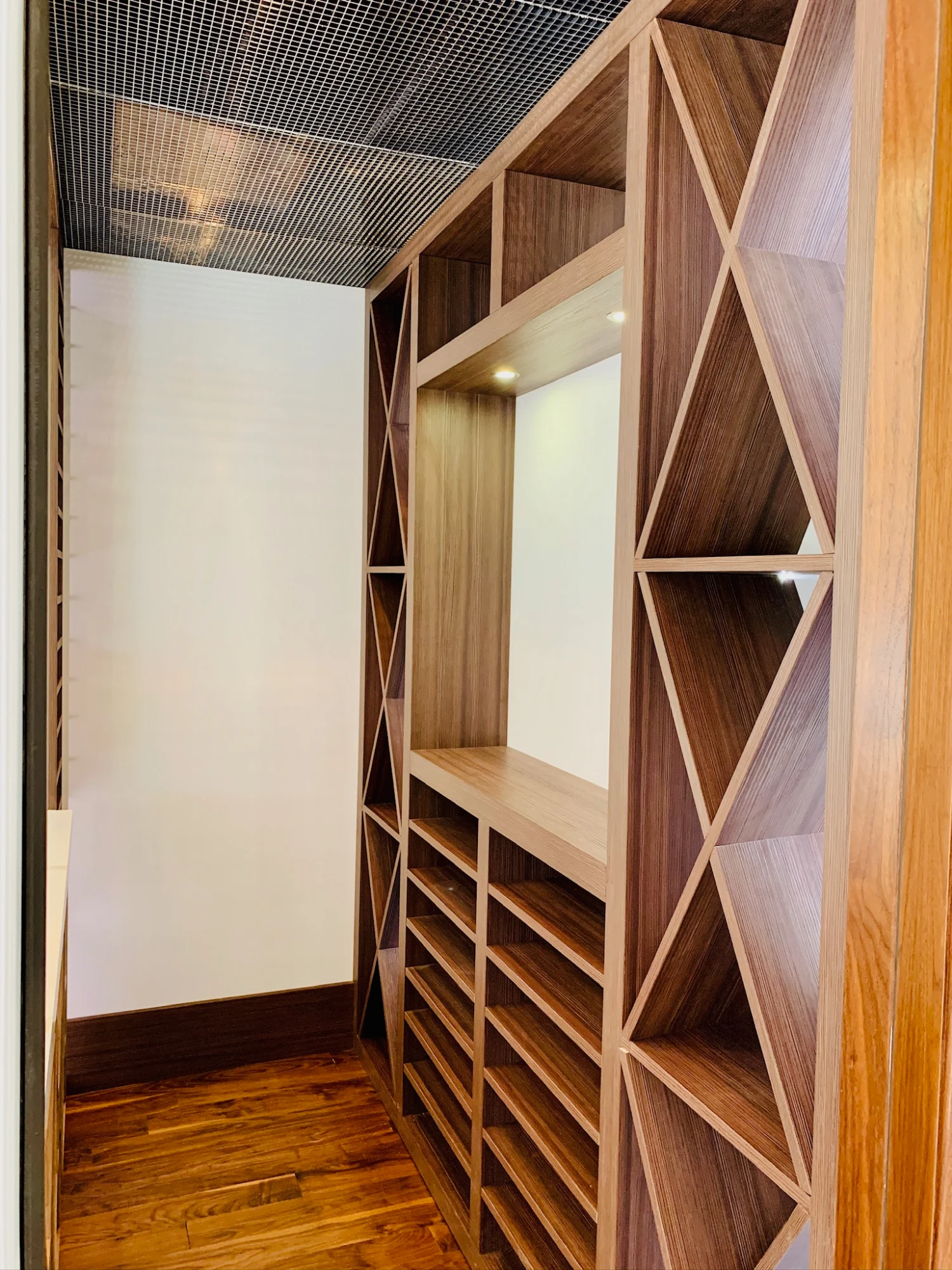 Custom lighted wood shelving and built-in storage cabinetry for a home bar